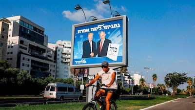A man cycles beneath an Israeli electoral billboard for the Likud party showing US President Donald Trump shaking hands with Prime Minister Benjamin Netanyahu. AFP