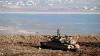 An Israeli soldier stands on a Merkava tank in the Israeli-annexed Golan Heights overlooking the Syrian village of Breqa yesterday. Israeli experts appear mixed on a possible escalation between Tel Aviv and Damascus.