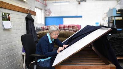 An employee works in the burling and mending room of Abraham Moon & Sons. Oli Scarff / AFP