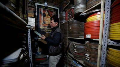 He looks through an archive of film reels.