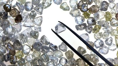 An uncut diamond is selected from a pile of colourless and coloured diamonds on a sorting table at DTC Botswana, a unit of De Beers. Bloomberg