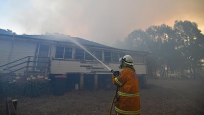 A firefighter hoses down property in the hope of saving it from nearby bushfires around the town of Nowra. AFP
