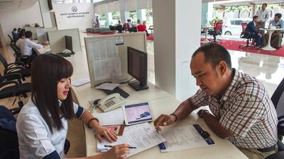 A car owner (right) takes out vehicle insurance from a private insurance company in Yangon. Romeo Gacad / AFP