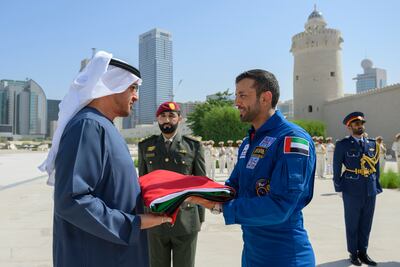 President Sheikh Mohamed is presented with the UAE flag by UAE astronaut Sultan Al Neyadi during a Flag Day ceremony, at Qasr Al Hosn. Photo: Presidential Court