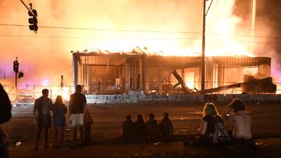 Protesters gather near the Minneapolis Police third precinct to watch a construction site burn. REUTERS