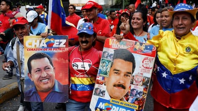 A woman holds placards with images of Venezuela's late president Hugo Chavez and current president Nicolas Maduro. Reuters