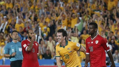 Australia's Robbie Kruse celebrates his goal between Oman players Jaber Al Owaisi, left, and Abdul Salam Al Mukhaini, right, during Australia's Group A win on Monday at the Asian Cup in Sydney. Jason Reed / Reuters / January 13, 2015