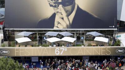People walk past the Festival Palace which displayed a giant canvas of the official poster of the 67th Cannes Film Festival featuring actor Marcello Mastroianni during the Film Festival in Cannes. Reuters