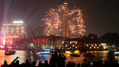 People watch fireworks explode over the Cairo Tower and the Nile River as New Year celebrations begin in Cairo. AP Photo
