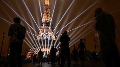 Attendees take pictures of the Eiffel Tower as lasers light up the sky during the opening ceremony of the Paris 2024 Olympic Games in Paris. AFP