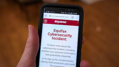 Close-up of the hand of a man holding a mobile phone open to the web site of credit bureau Equifax, providing steps for consumers to take following a major security breach at the company. Photo by Getty Images