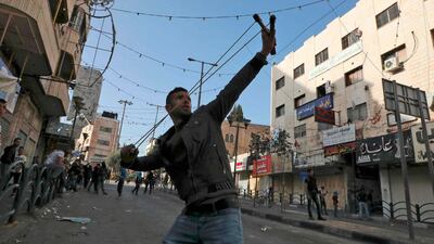 A Palestinian youth uses a slingshot to hurl a stone towards Israeli security forces during clashes in the West Bank city of Hebron as Palestinians stage a "day of rage" against a recent US decision to no longer consider settlements in the West Bank illegal. AFP