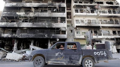 Rebels drive past buildings damaged during heavy fighting earlier this year between Libyan rebels and Gaddafi loyalists in the centre of Misrata. Darren Whiteside / Reuters