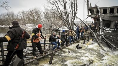 Members of a Ukrainian civil defence unit pass new assault rifles to the opposite side of a blown up bridge on Kyiv's northern front on March 1. AFP