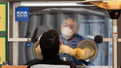 A healthcare worker standing inside a container collects a sample from a visitor at a temporary Covid-19 testing station outside Seoul City Hall in Seoul. Bloomberg