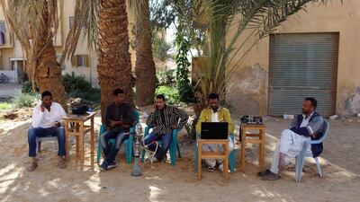 Men smoke and use their mobile phones as they sit at a small cafe in Siwa.