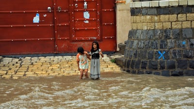 Girls cross a flooded street in the old city of Sanaa. AFP