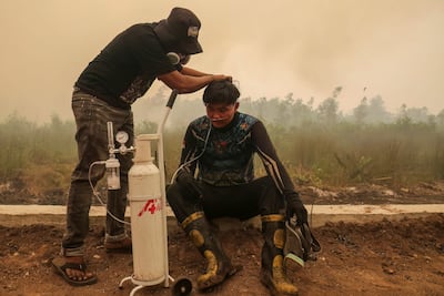 A volunteer from the Central Kalimantan Forest and Land Fire Smoke Response Coalition provides mobile oxygen relief to a firefighter while battling forest and land fires in Palangkaraya, Central Kalimantan. AFP