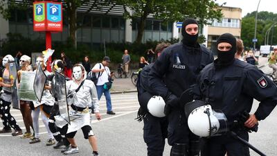 German riot police officers stand next to protesters during demonstrations against the G20 summit in Hamburg on July 8, 2017. Pawel Kopczynski / Reuters