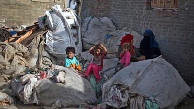 Young Palestinian children sit on plastic sacks of garbage outside a house in Gezirat al-Fadel village.