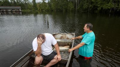 Stephen Gilbert, left, and his father-in-law sit in front of their flooded property. Floodwaters are starting to recede in most of the Houston area after the remnants of Tropical Storm Imelda flooded parts of Texas. AP