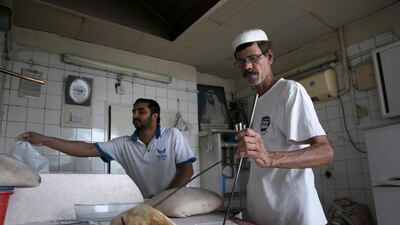 Kashmiri baker Ghulam Fareed, 51, prepares fresh flat bread for a customer as he and his assistant work away at his brother's bakery, the Mohammed Murid Abdul Karim bakery in central Abu Dhabi. Silvia Razgova / The National