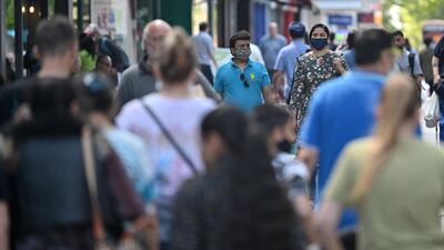 Pedestrians, some wearing masks, walk past shops in Hounslow, west London. AFP