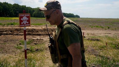 A Ukrainian soldier walks near a post warning about landmines in a field on the outskirts of Kyiv, Ukraine in June. AFP