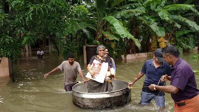 An elderly woman is rescued in a cooking utensil after her home was flooded in Thrissur, Kerala. AP Photo
