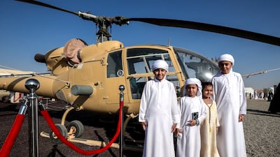 Visitors pose in front of a Gazelle helicopter on display. This helicopter participated in the Liberation of Kuwait campaign in 1990