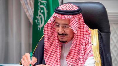 King Salman signs the 2021 state budget following a virtual cabinet meeting in Riyadh, late Tuesday. Saudi Press Agency via AP