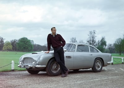 Sean Connery poses with an Aston Martin during the filming of 'Goldfinger' in 1964. Alamy