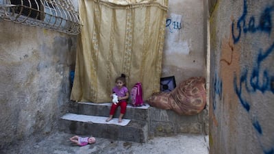 Nur Abu Sneineh is sitting outside her home squeezing a toy sheep as she sits at the entrance of her family’s home on September 27, 2015.