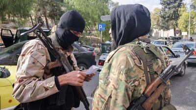 Fighters affiliated with Syria's new administration checking a driver's paperwork in western Damascus, in December. AFP