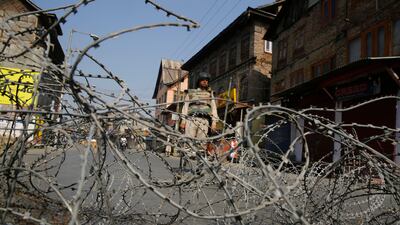 An Indian paramilitary soldier stands guard near barbed wire set as a temporary barricade during restrictions in downtown of Srinagar, the summer capital of Kashmir. Farooq Khan / EPA