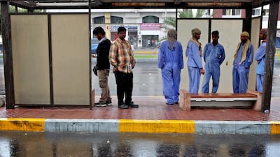 Commuters take shelter at a bus stop as rain and high winds drench Abu Dhabi this afternoon. Brian Kerrigan / The National