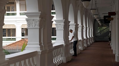An employee stands in an external corridor at the Raffles Hotel. Bloomberg