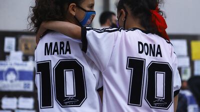 Twin sisters Mara and Dona Rotundo, named after Diego Maradona, embrace outside the clinic. Reuters