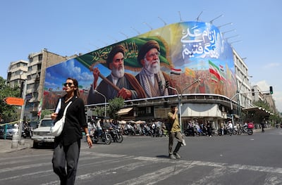 Iranians walk past a billboard showing late supreme leaders Ruhollah Khomeini and Ali Khamenei. EPA