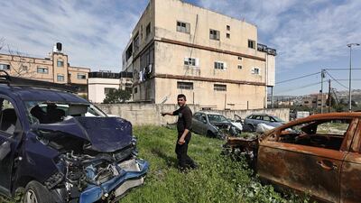 Palestinian mechanic and garage owner Motaz Qassrawi stands amid cars damaged during an attack by Israeli settlers in Huwara town in the occupied West Bank on March 13, 2024. AFP