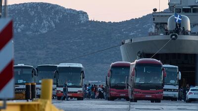 Migrants wait to board on buses after their disembarkation at the port of Elefsina, near Athens, on Saturday. AP