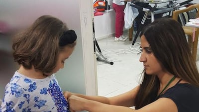 Maria Iqbal, measuring a Syrian refugee girl for a ruffled skirt.