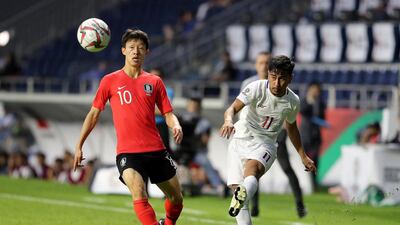 South Korea's Lee Jae-sung, in red, vies for the ball with Daisuke Sato of the Philippines.