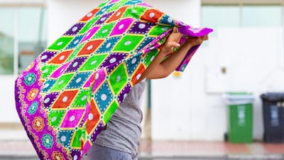 A lady covers her hair as the rain comes down in Dubai. Chris Whiteoak / The National