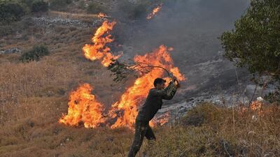 A handout picture released by the official Syrian Arab News Agency (SANA) shows a Syrian man attempting to put off a fire on a hill in Ain Halaqim, in the western countryside of Syria's Hama governorate. AFP