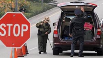 Police officers search a passenger car arriving at Los Angeles International Airport at a security checkpoint on December 26.