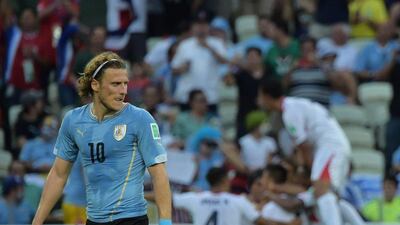 Diego Forlan walks to the centre circle to restart the game as Costa Rica players celebrate a goal in their 3-1 win. Gabriel Bouys / AFP Photo