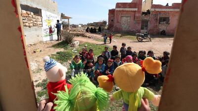 Syrian children watch a puppet show performed by a local theatre group amidst the ruins of buildings destroyed during Syria's civil war, in Idlib, on March 30. AFP