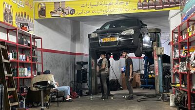 Young mechanics work on a car at the Qalandiya refugee camp. Khaled Yacoub Oweis / The National
