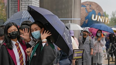 Women wear face masks to help protect themselves from Covid-19 as they line up to enter a merchandise store at Universal Studios Beijing. AP Photo